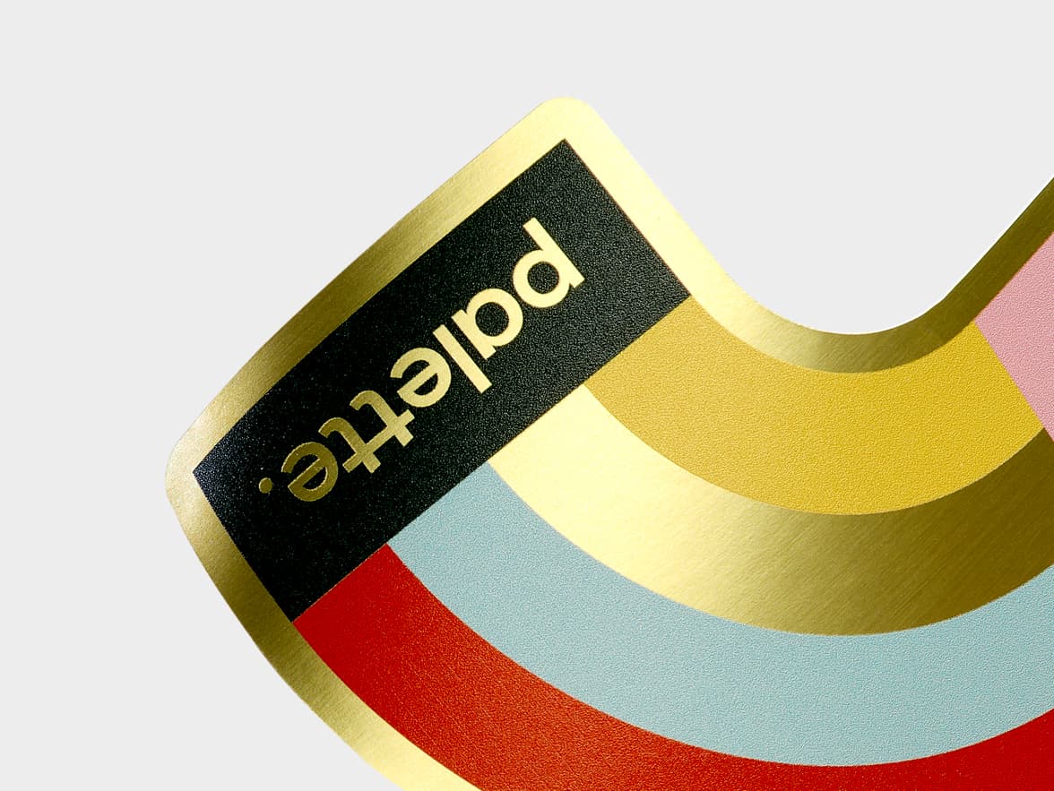 A close up image of a customized gold metallic sticker in the design of a half rainbow.