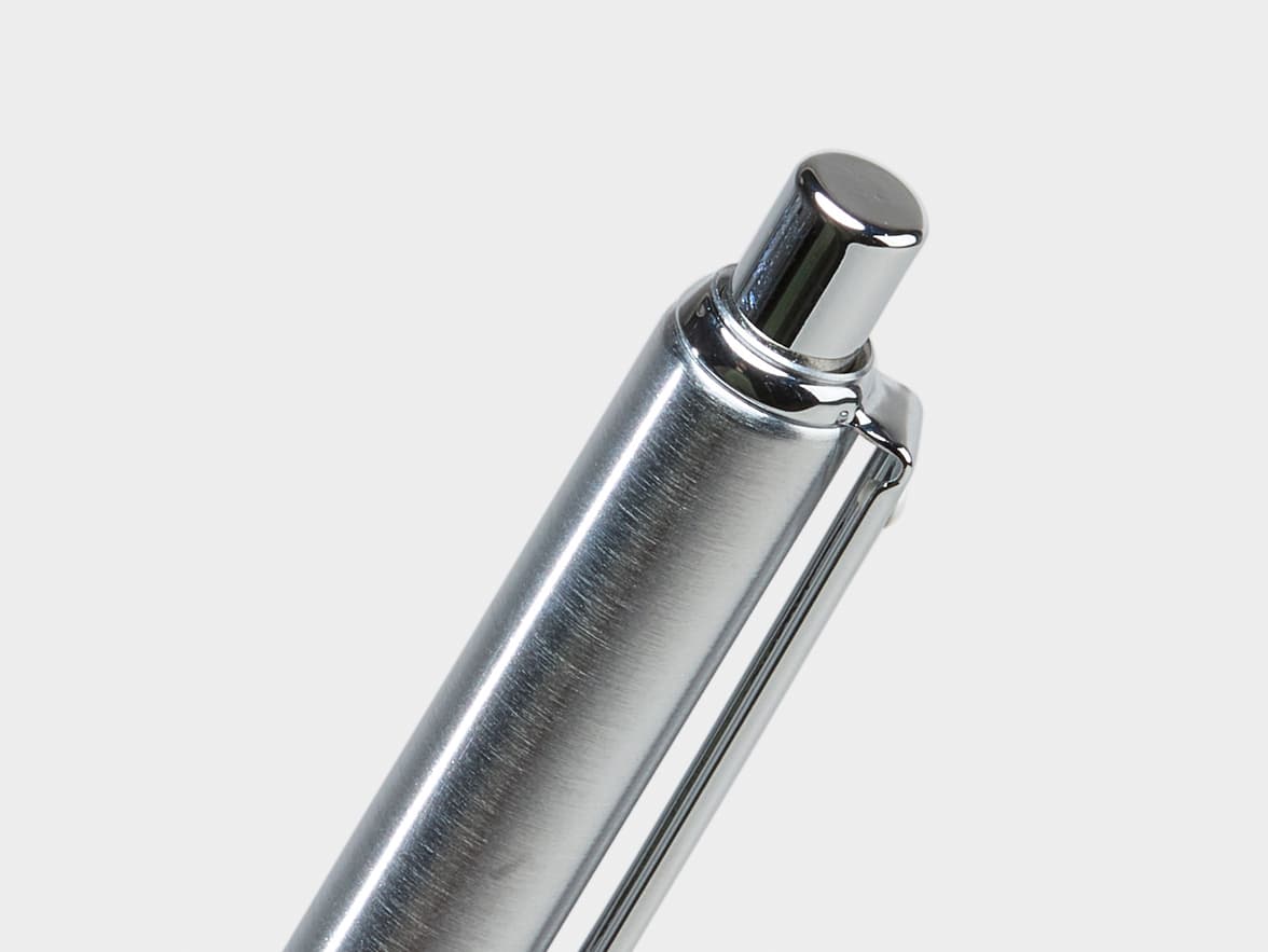 A close-up of the top part of a silver-colored, brushed metal pen with a shiny chrome cap and clip.