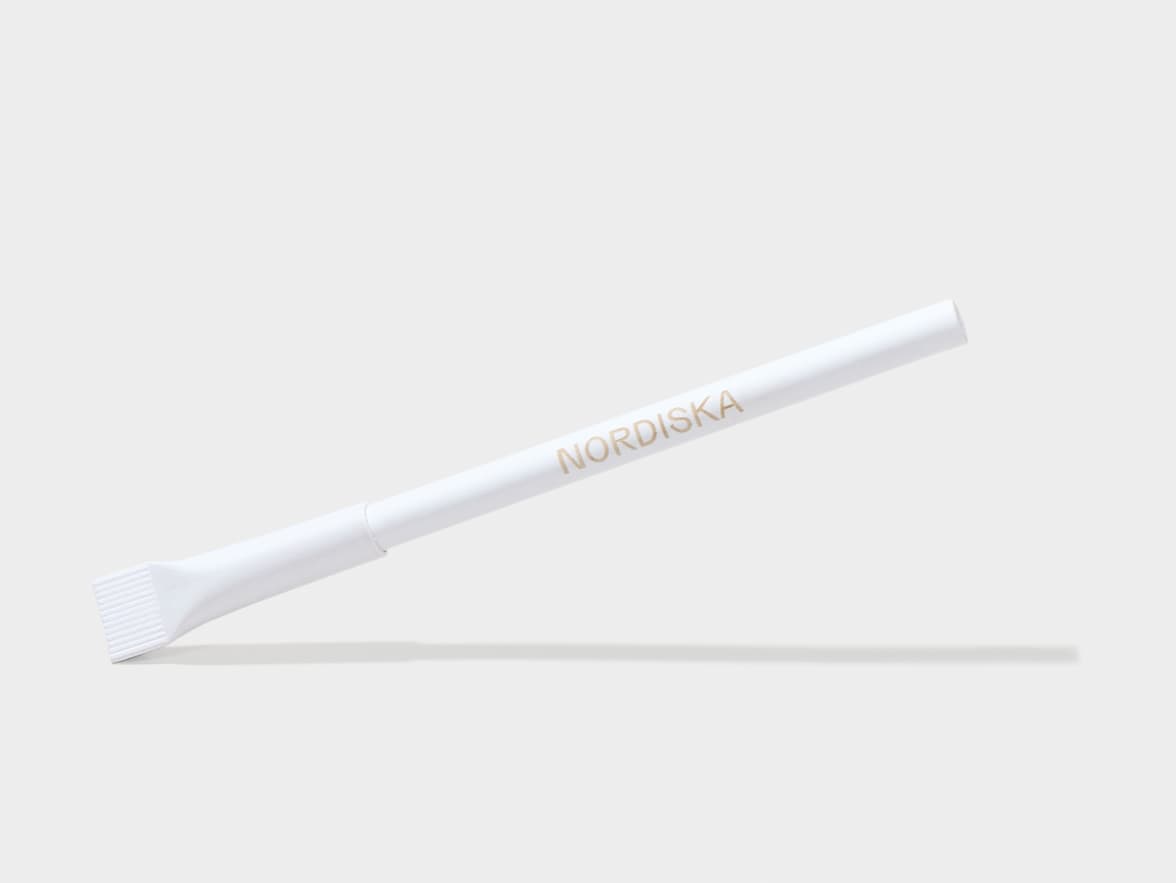 A white, slender NORDISKA brand pen with a flat, ribbed tip.