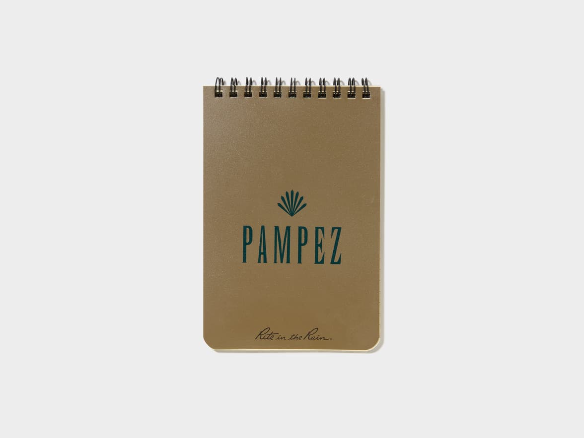 A brown spiral-bound notebook with a dark teal palm frond logo and the text "PAMPEZ" above "Rite in the Rain.".
