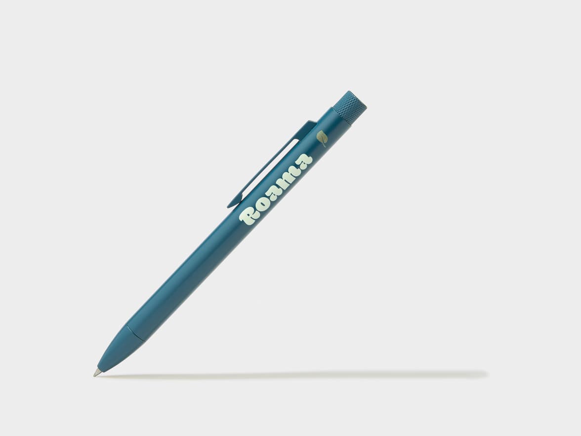 A teal pen with the brand name "Roana" and a leaf icon printed on it, resting at an angle on a white background, casting a shadow.
