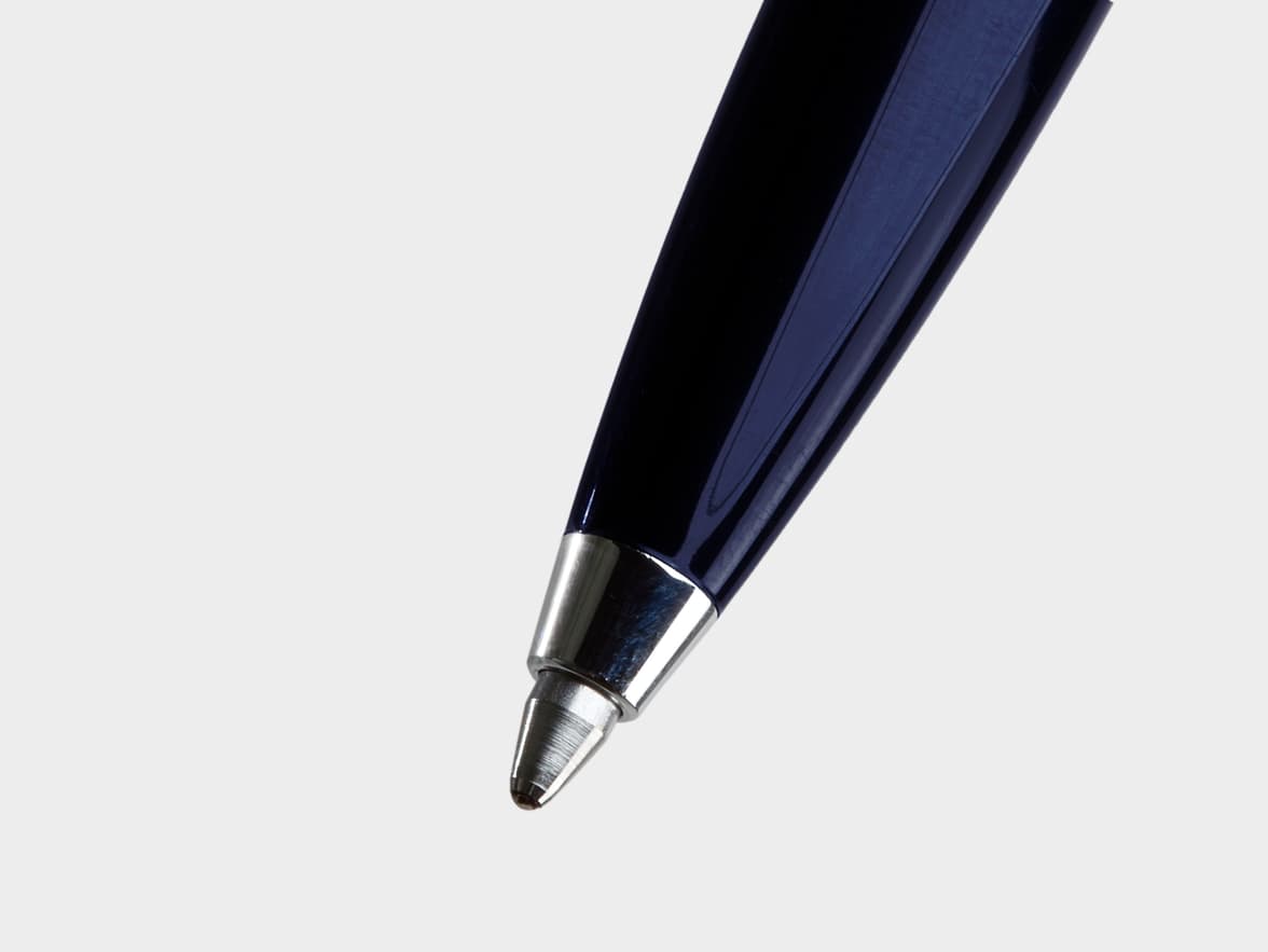 Close-up of the silver tip of a dark blue pen on a white background.