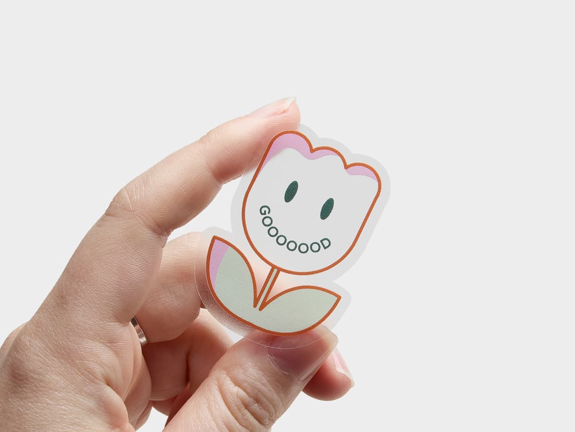 A hand holding a customized clear die cut sticker with the design and in the shape of a flower.