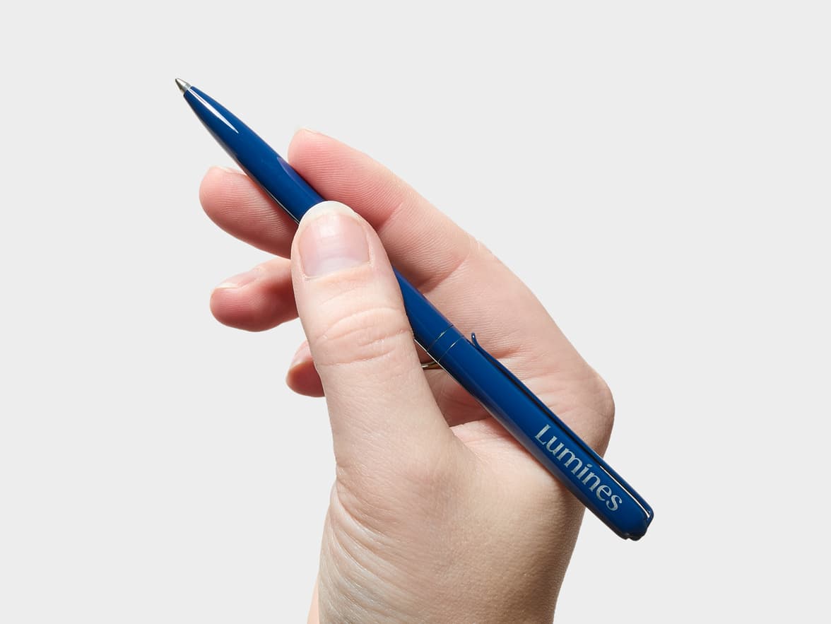 Hand holding a blue "Luminés" pen.