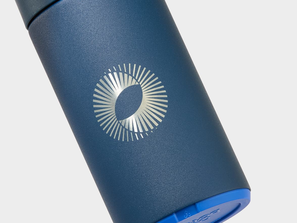 A dark blue textured bottle with a silver circular logo.