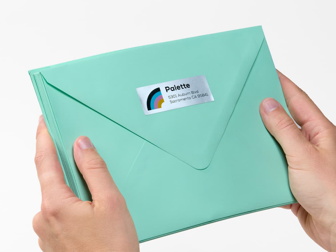 Hands holding an envelope with a customized rectangular silver sticker on it.