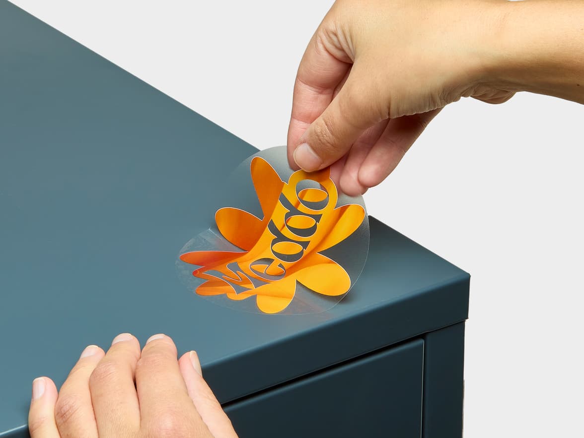 A hand placing a customized round clear sticker onto a box.