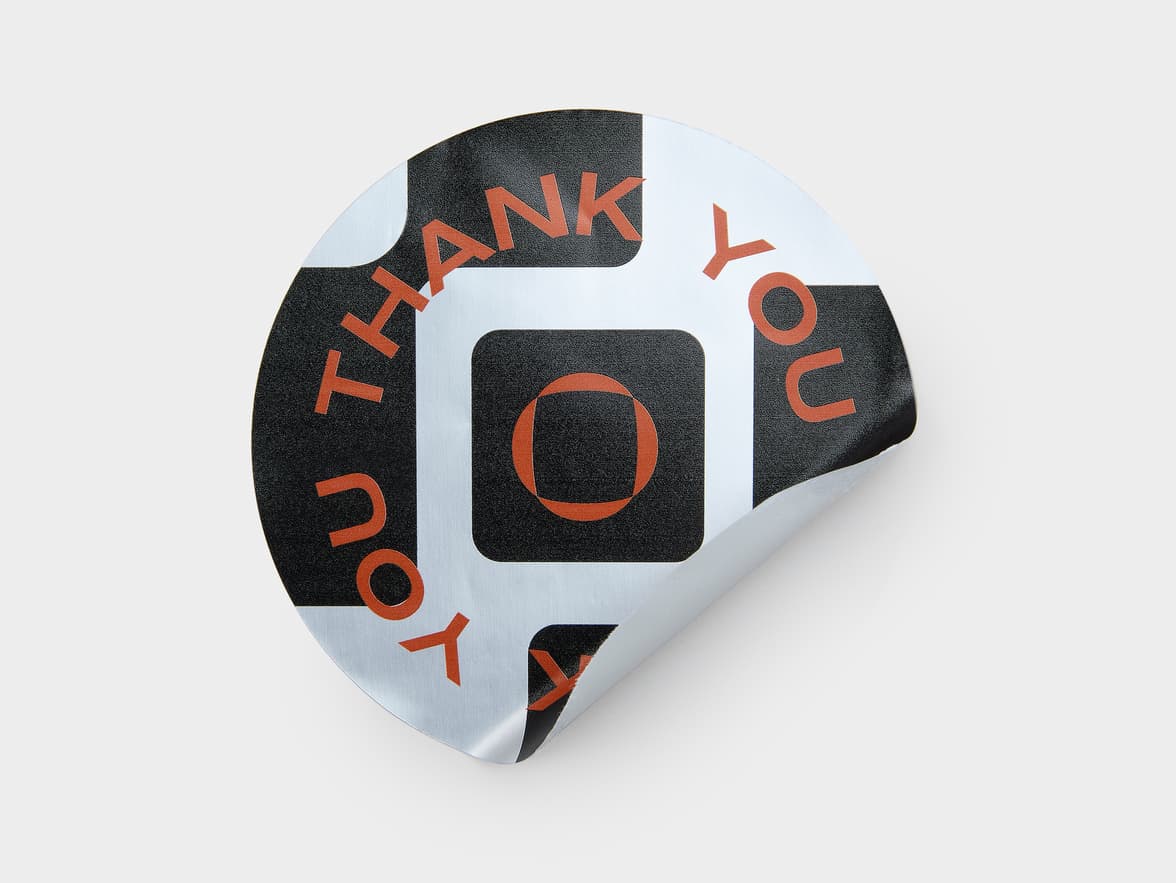 A large round silver metallic sticker with black customization.