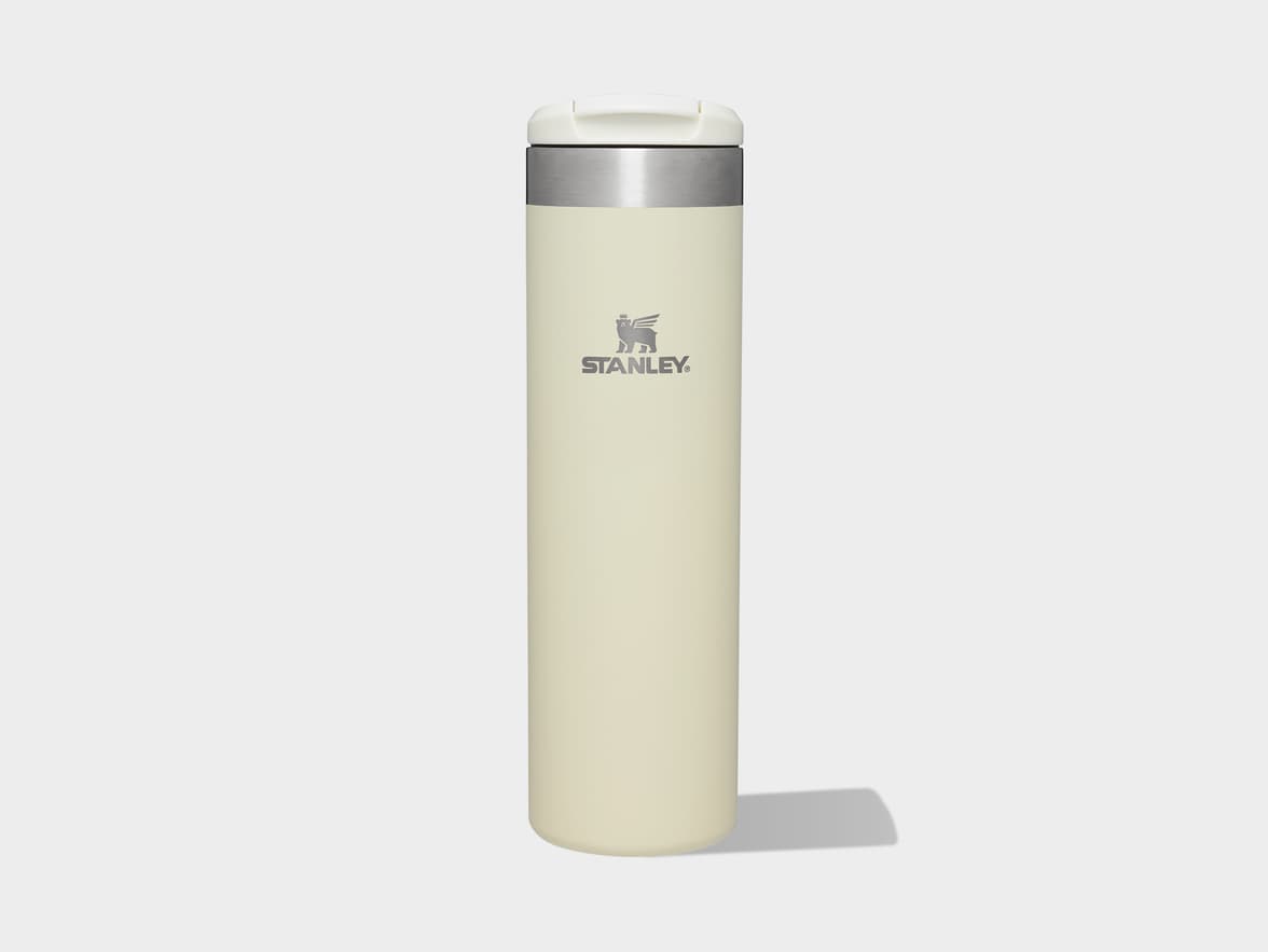 Light beige Stanley travel mug with a white lid and silver band, featuring the Stanley logo and text.