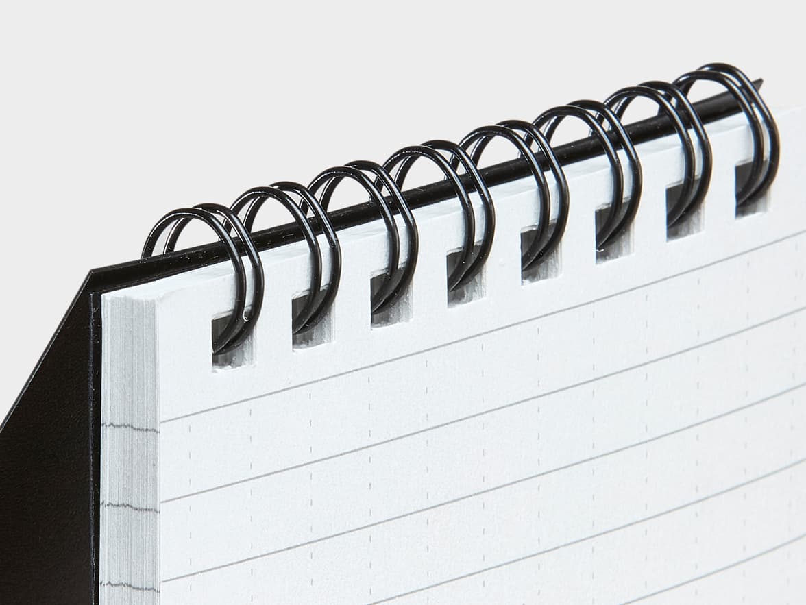Open, lined spiral notebook with a black cover and black spiral binding.