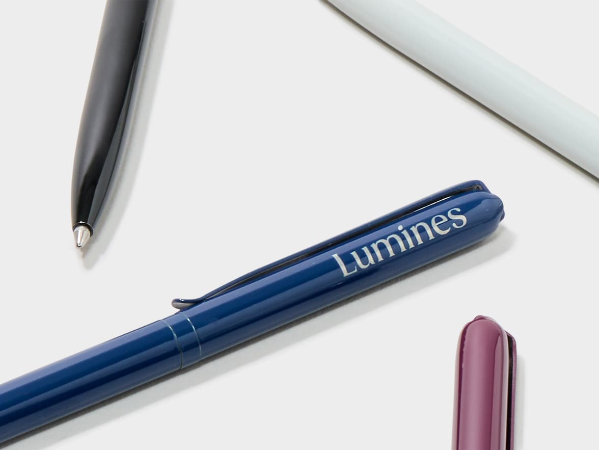 A blue pen with "Lumines" branding, with other pens in the background.