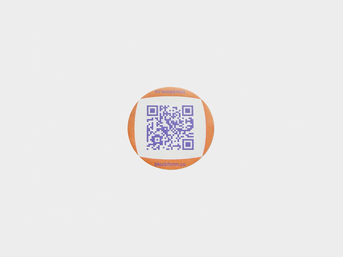 A customized clear round sticker with a purple QR code printed on it.