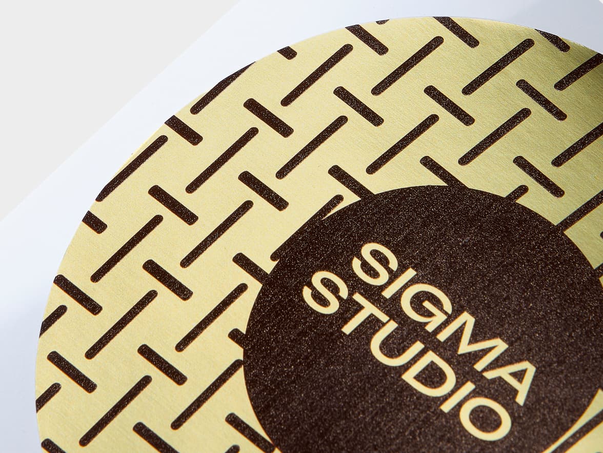 A close up image of a large round gold metallic sticker with brown customization.