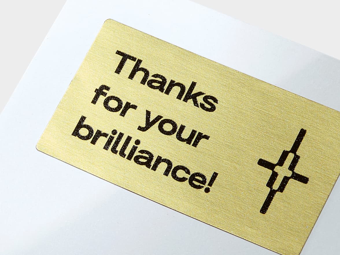 A close up image of a gold metallic sticker with black customization.