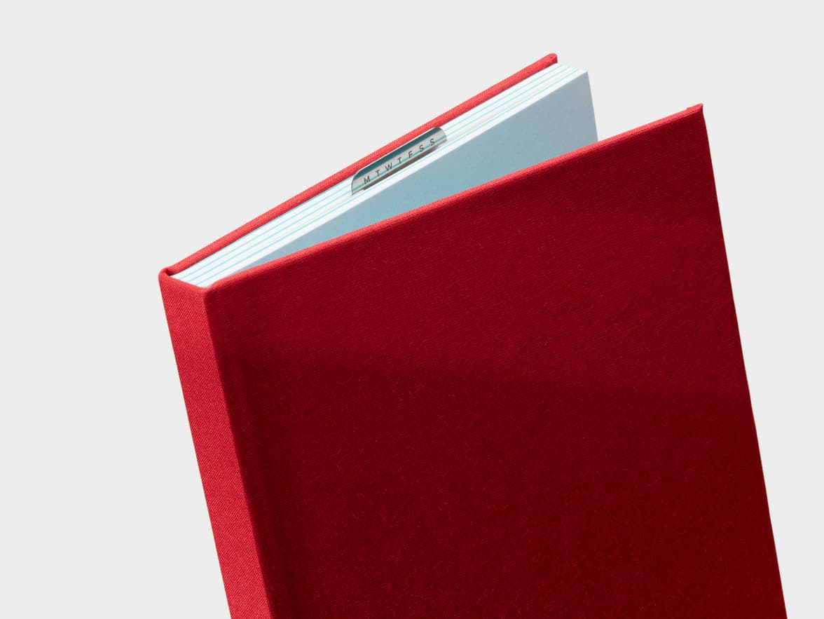 Half Opened Berry Red Cloth Planner with a silver clip sticking out