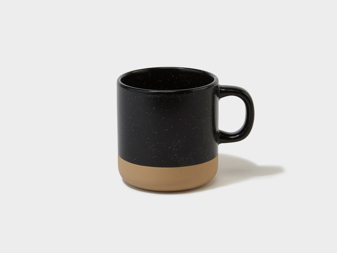 A black speckled ceramic mug with a tan base and handle.