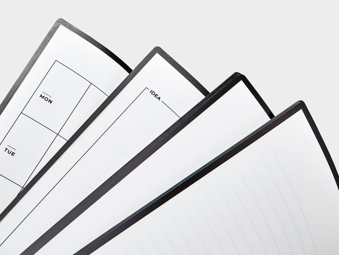 Several open pages of a minimalist notebook or planner, showing sections labeled "MON", "TUE", and "IDEA", along with dotted lines for writing.