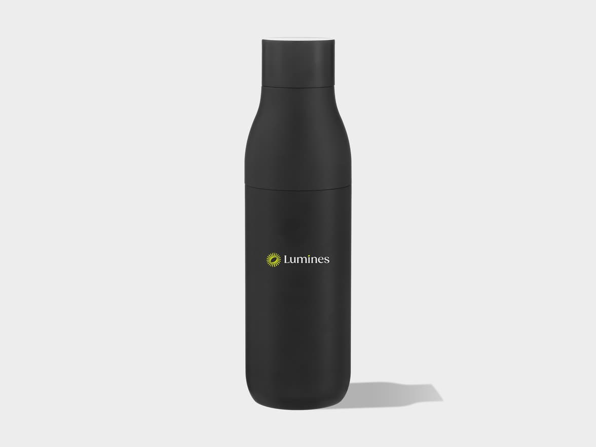 A black insulated water bottle with a white cap, featuring a yellow sun-like logo and the word "Lumines" in white on its side, stands upright on a light gray background with a shadow extending to the right.