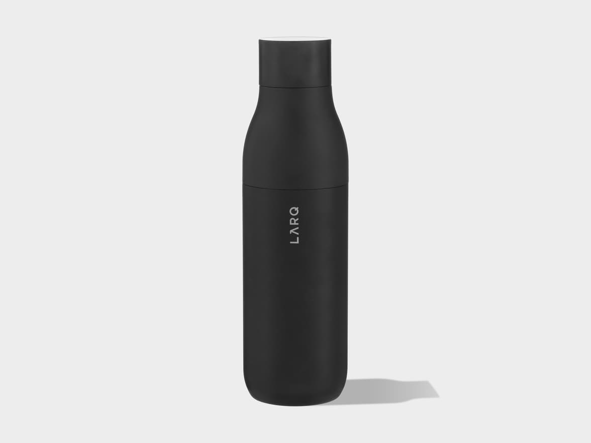 A black LARQ self-cleaning water bottle stands upright on a plain light grey background, with a soft shadow extending to its right.