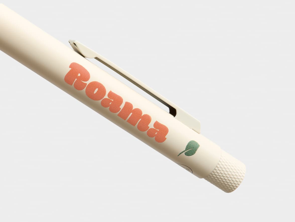 Creme-colored pen with "Roama" in orange text and a green leaf logo.