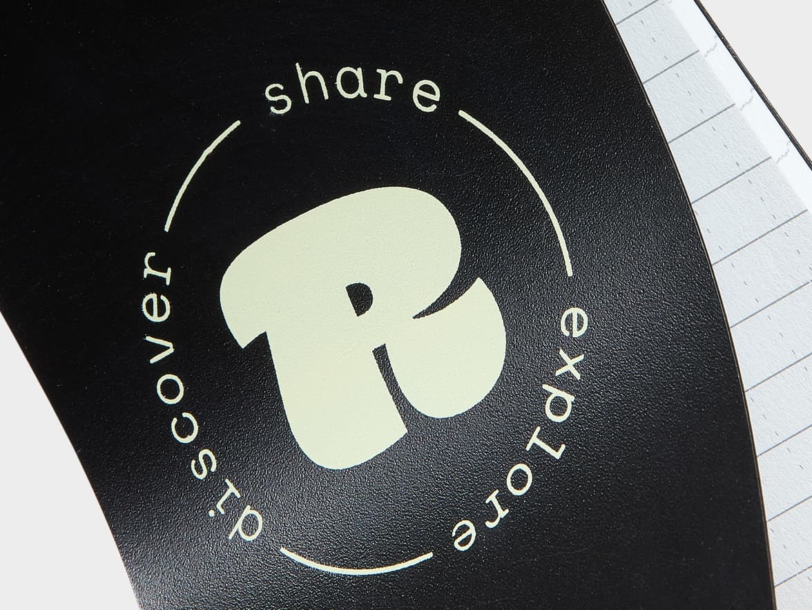 Black notebook cover with a stylized 'R' surrounded by the words "share discover explore".