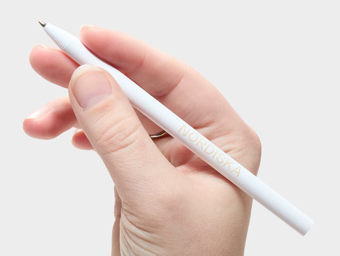 A hand holding a white NORDISKA pen.
