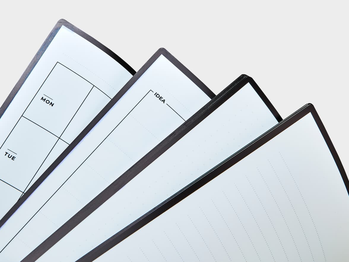 Notebook pages fanned out, showing planner sections labeled "MON", "TUE", and "IDEA".
