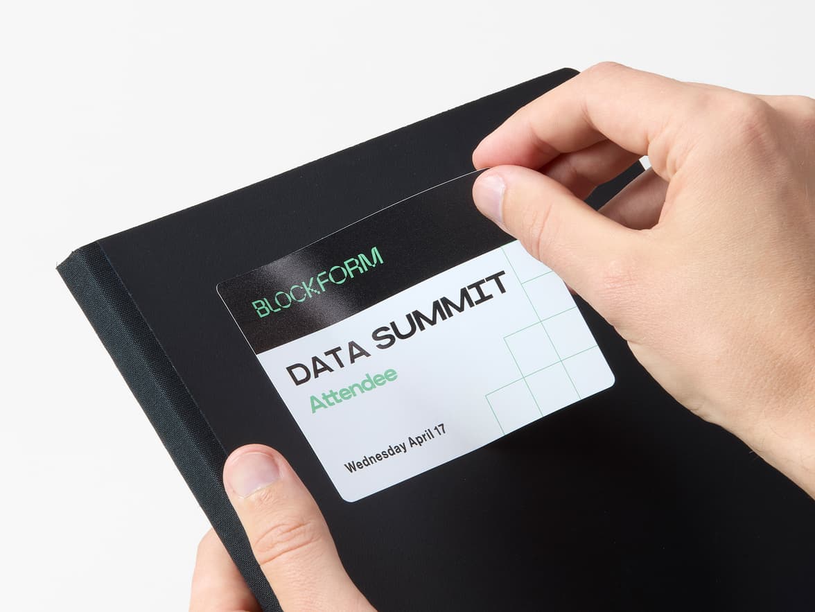 Hands placing a name tag style customized rectangular coated sticker onto a notebook.