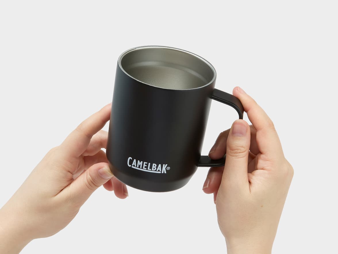 A black Camelbak mug with a silver interior, held by two hands.