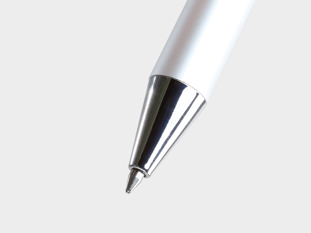 A close-up shot of the shiny chrome tip and matte silver body of a ballpoint pen, set against a plain light gray background.