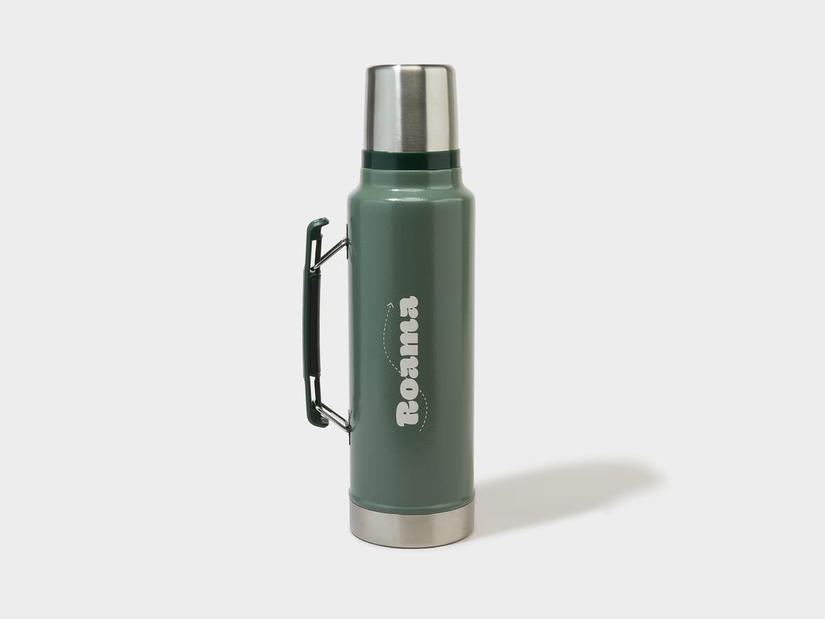 A dark green thermos with a stainless steel top and base, featuring a black handle and the brand name "Roama" in white text.