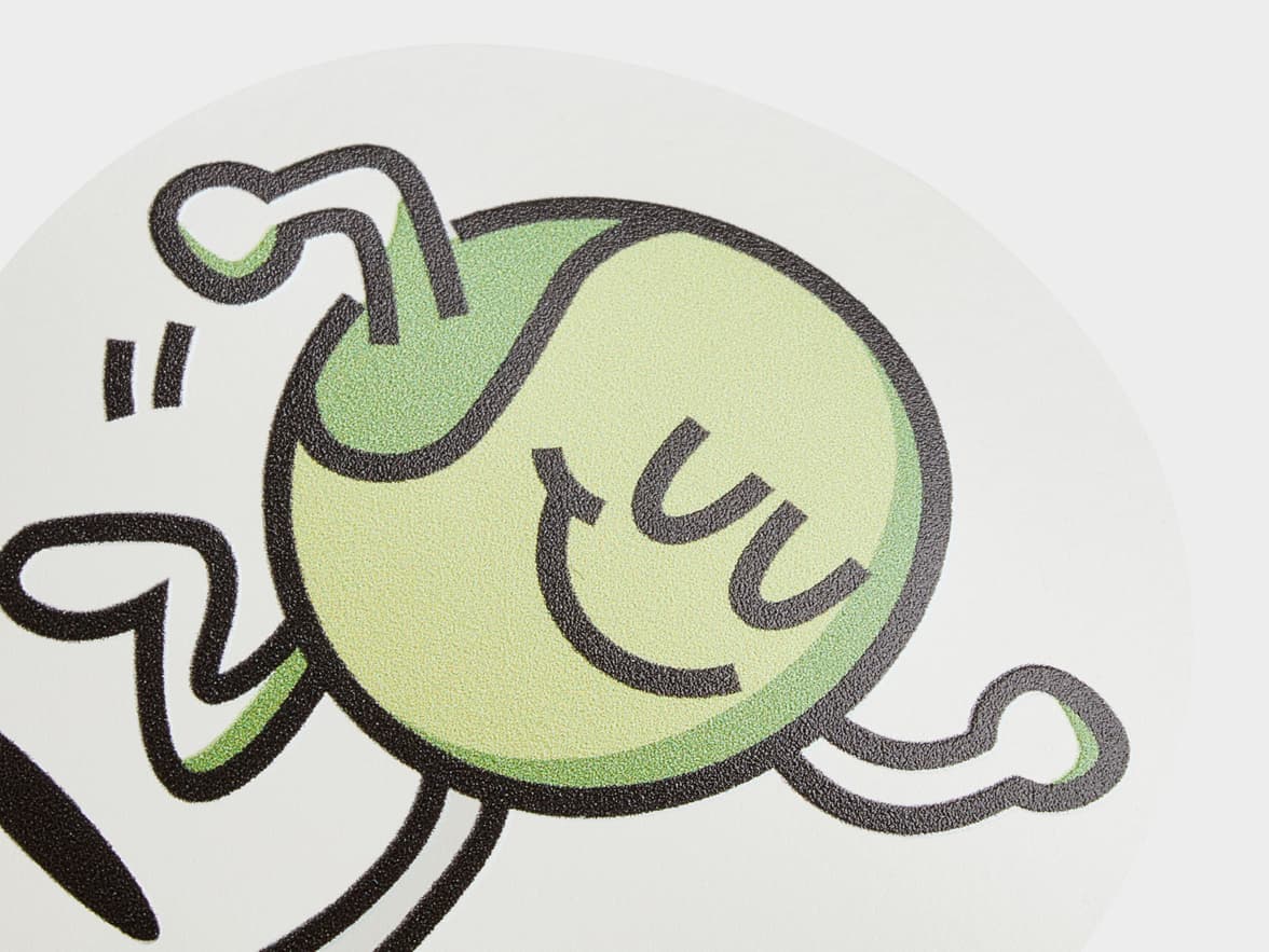 A close up of a customized clear round sticker with a green cartoon character printed on it.