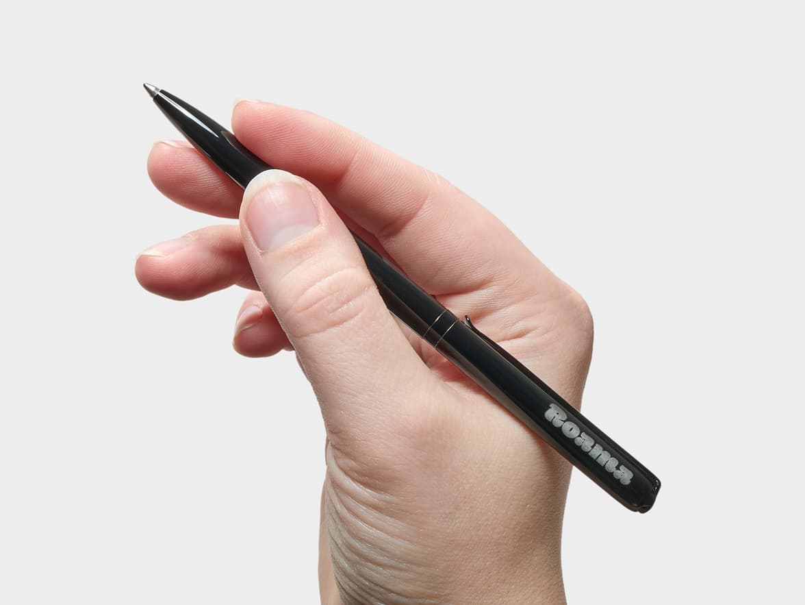 Hand holding a black Roamer pen.