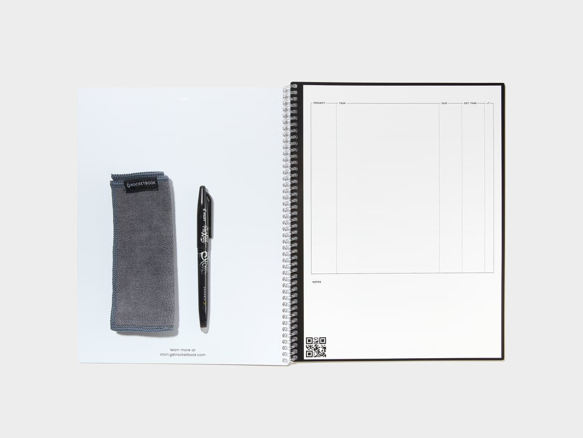 An open Rocketbook notebook displaying a project/task planning page with a QR code, accompanied by a Rocketbook microfiber cloth and a Pilot Frixion pen. Text visible includes 'start.getrocketbook.com'.