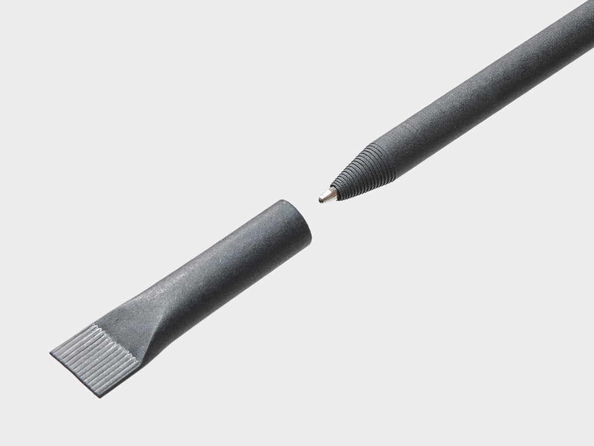 A dark grey, textured pen with a metal ballpoint tip, shown next to its detached cap which has a flat, ridged end.