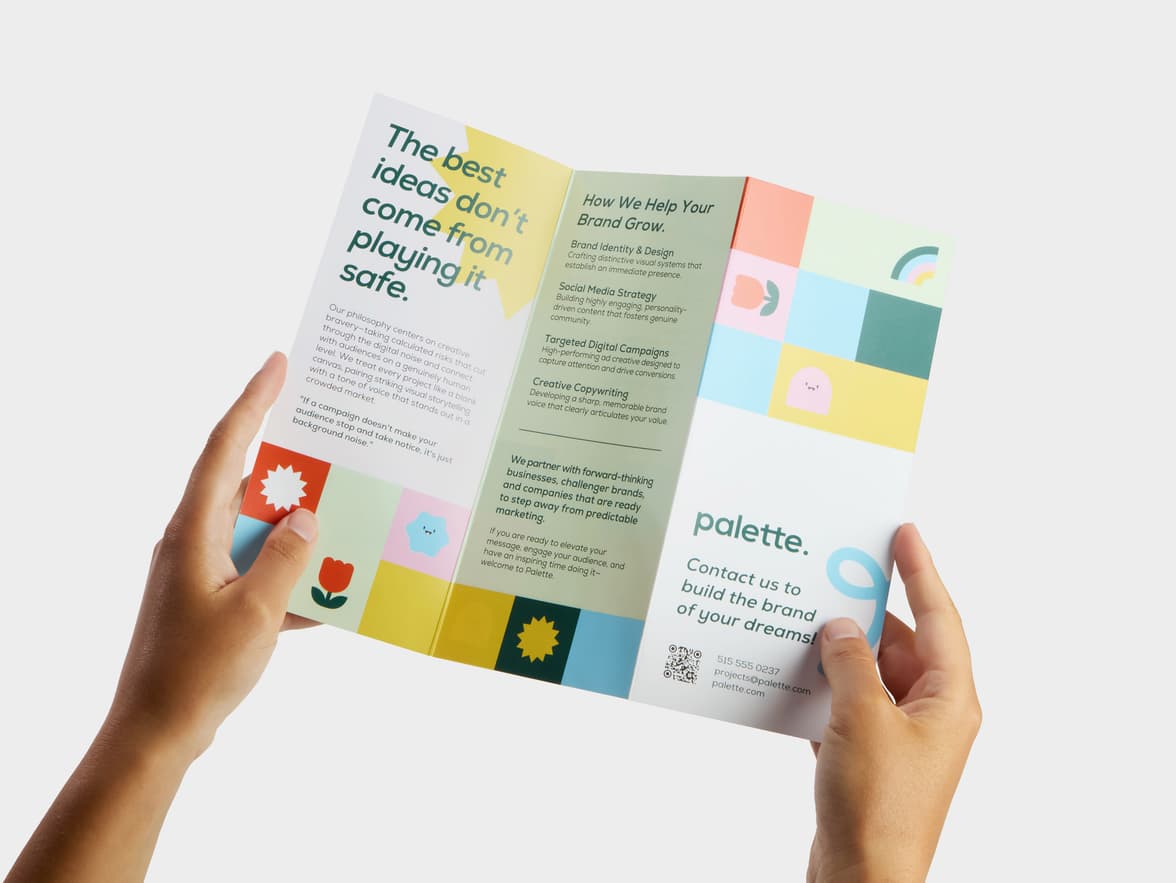 A pair of hands holding open a Z-Fold Original Gloss Brochure.