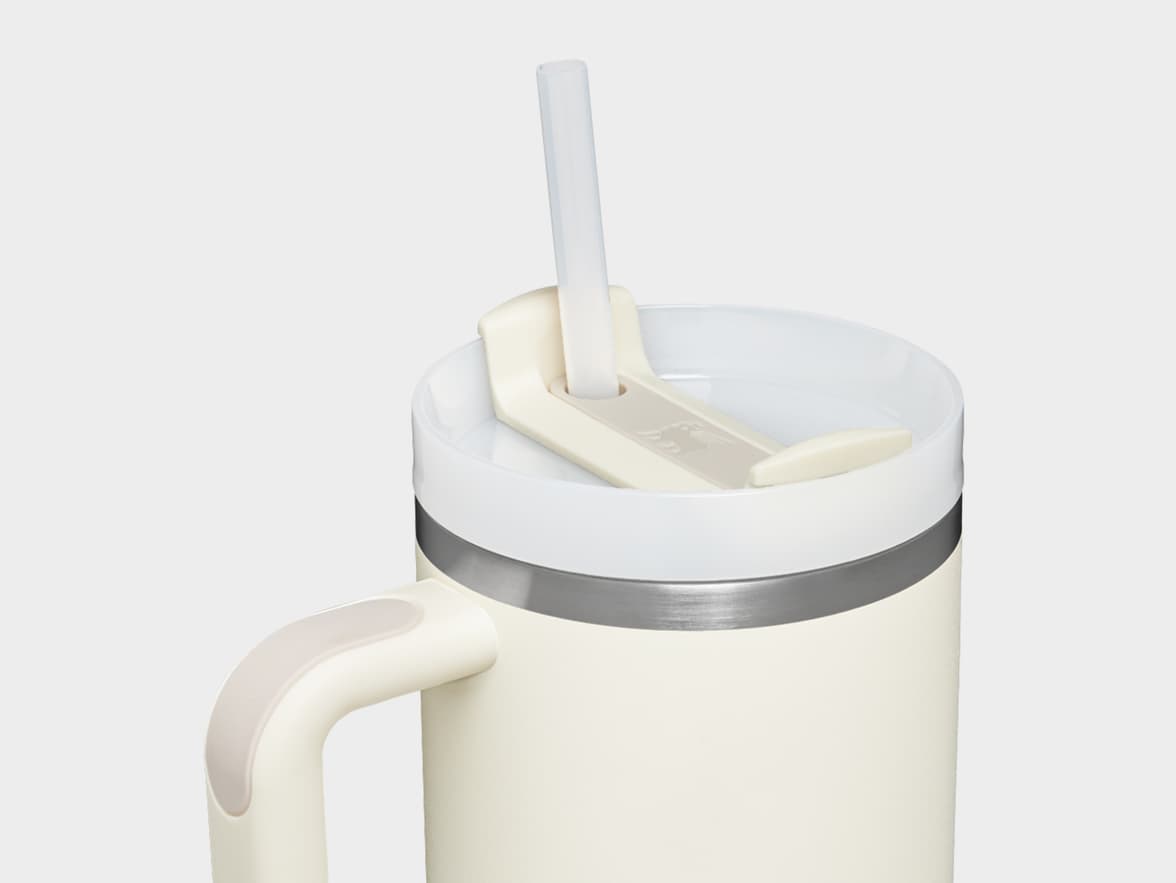 A cream travel mug with a handle, white lid, and clear straw.