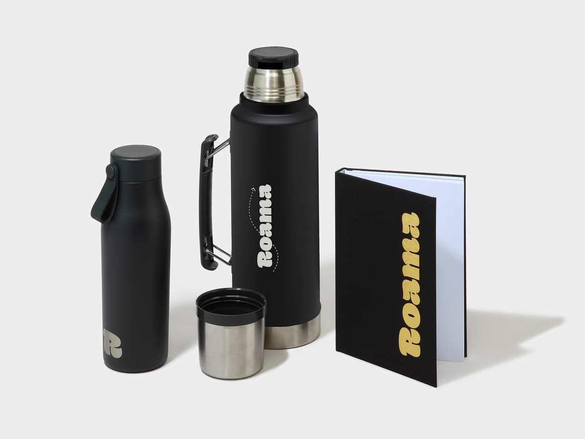 Black water bottle with an R logo, a large black thermos branded "Roama", and a black notebook also branded "Roama".
