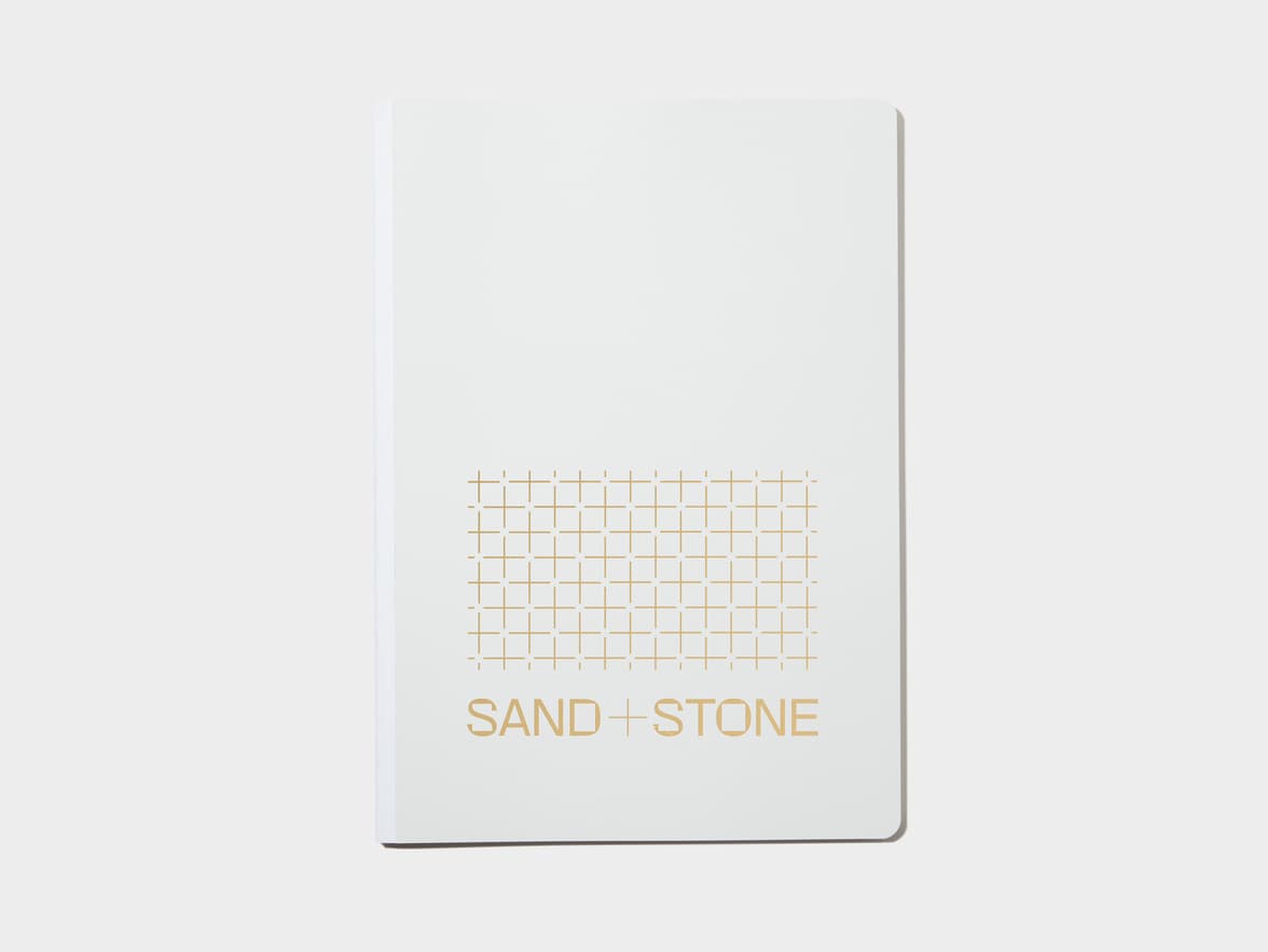 A large cloudy grey softcover notebook with gold foil customisation.