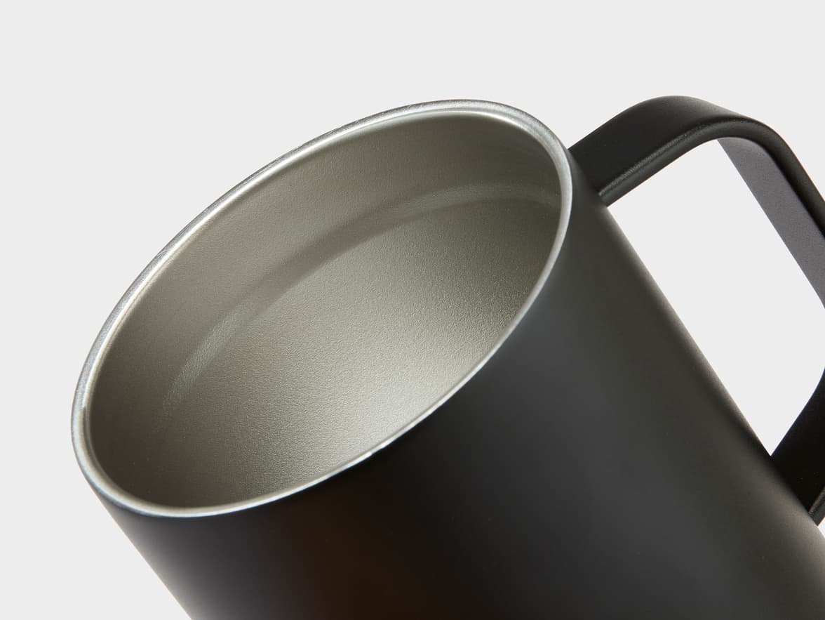 A close up of the top of a black travel mug.