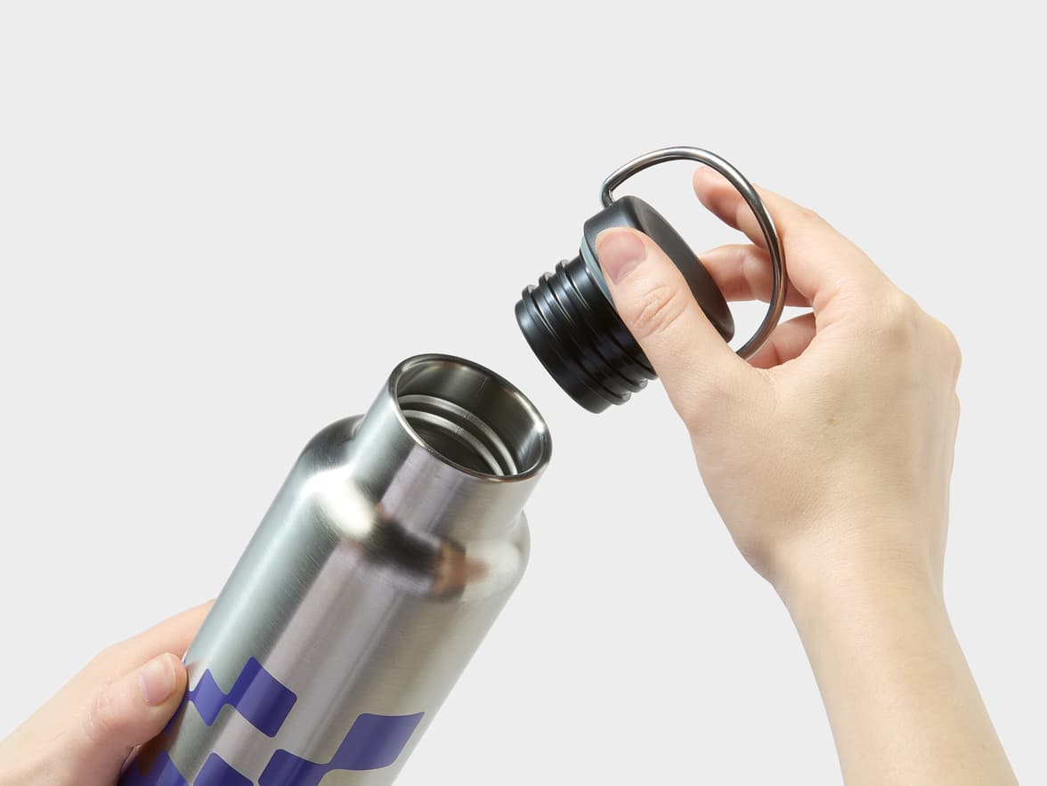 Stainless steel bottle with a purple geometric pattern, being opened.