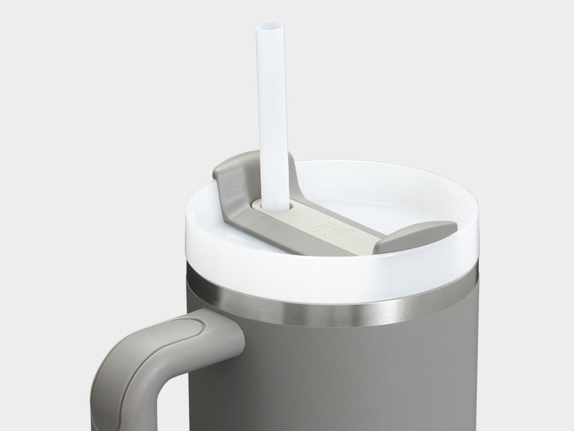 A grey tumbler with a white lid, white straw, and grey handle.