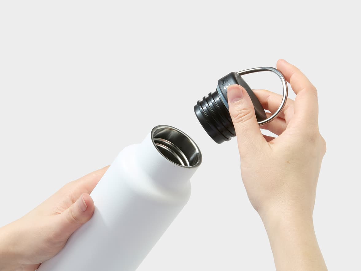 White Klean Kanteen bottle being opened by hands.