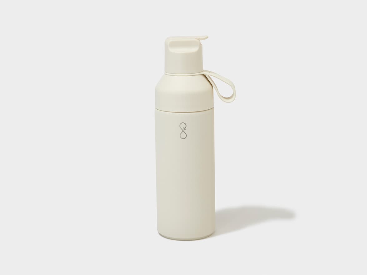 A cream-colored water bottle with a pop-top lid, a loop handle, and a grey circular arrow logo on the front.