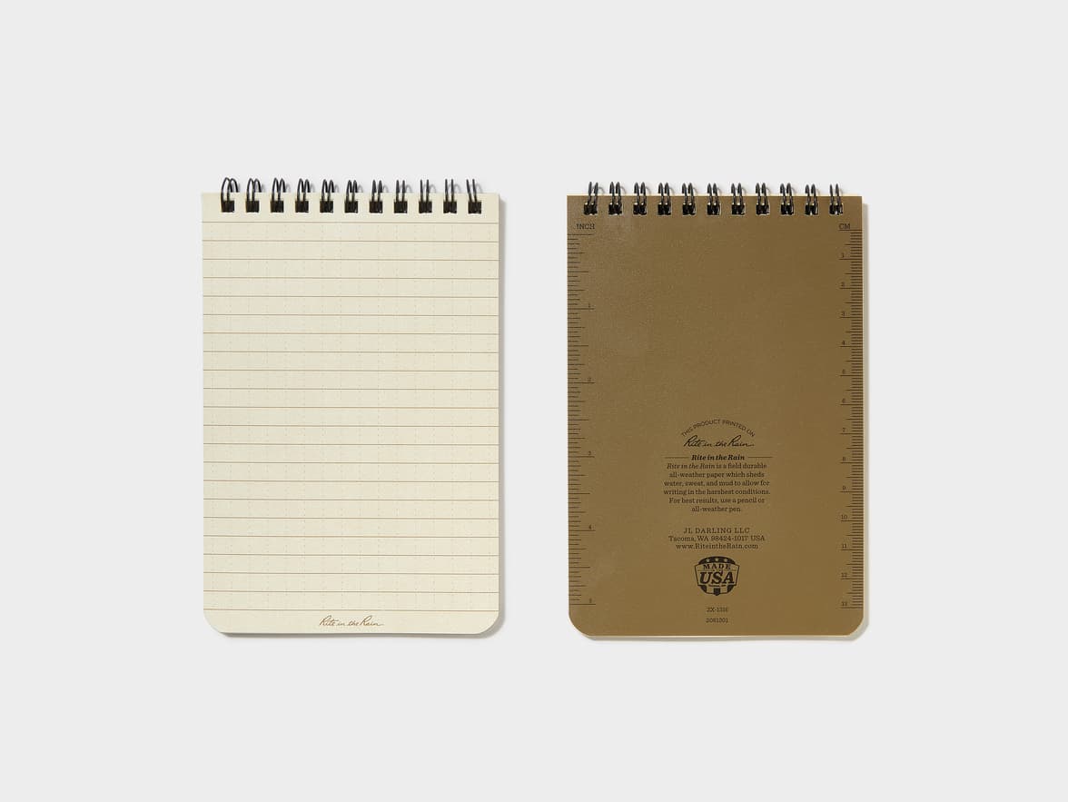 A spiral-bound "Rite in the Rain" notepad, shown front and back, with lined, all-weather paper on the front, and a back cover featuring rulers and text describing it as "field durable all-weather paper" by "JL DARLING LLC", "Made in the USA".