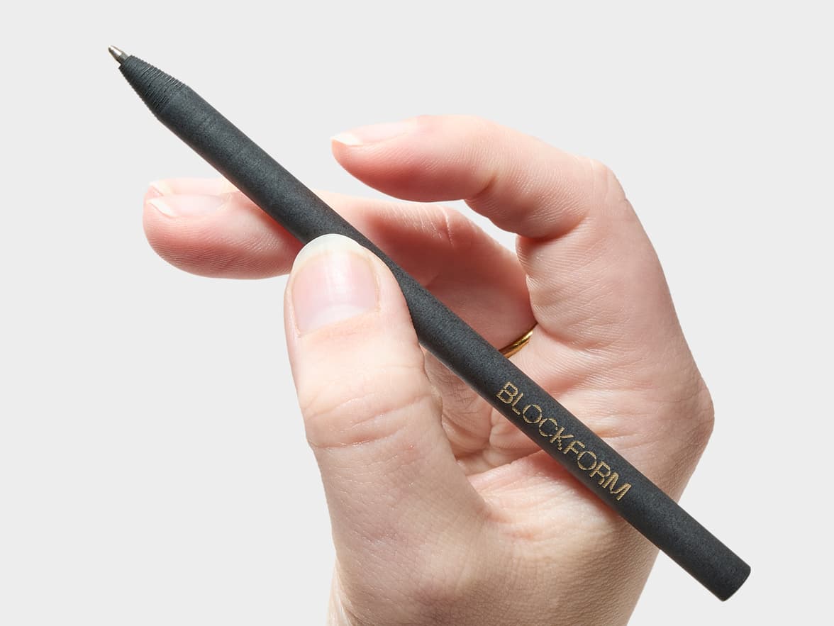A dark pen with "BLOCKFORM" written on it, held by a hand.