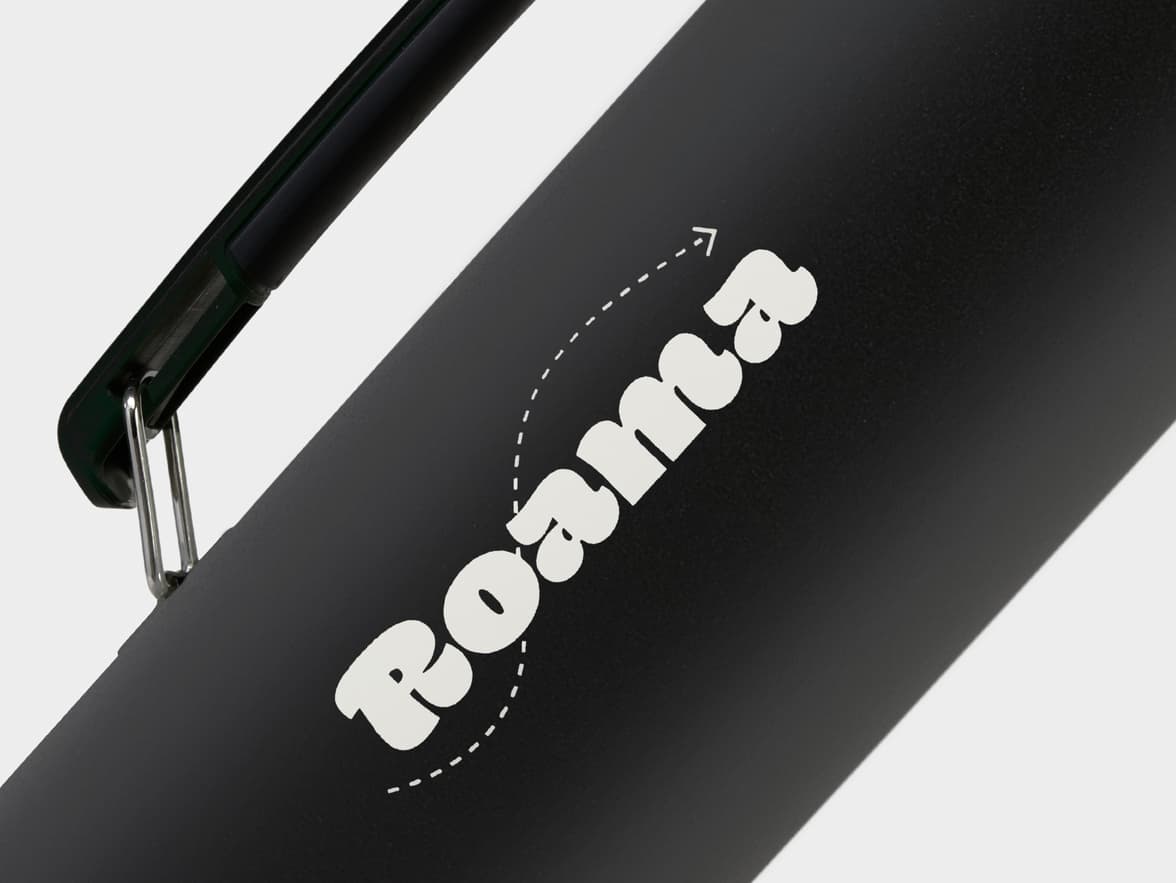 A black water bottle with the brand "Roama" in white text, accompanied by a white dashed arrow.