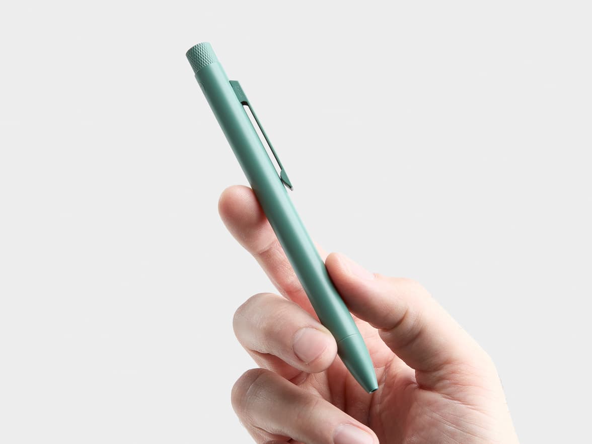 A hand holds a green pen with "CHINA" written on its clip.