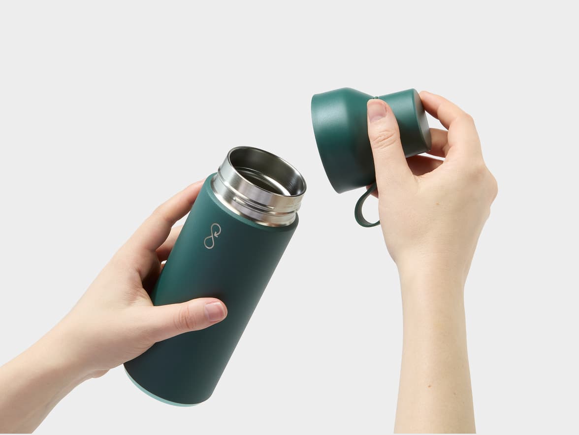 Hands opening a green insulated bottle with a silver infinity loop logo.