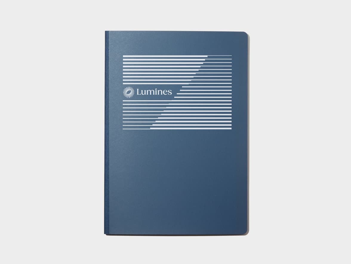 A large midnight blue softcover notebook with white foil customisation.